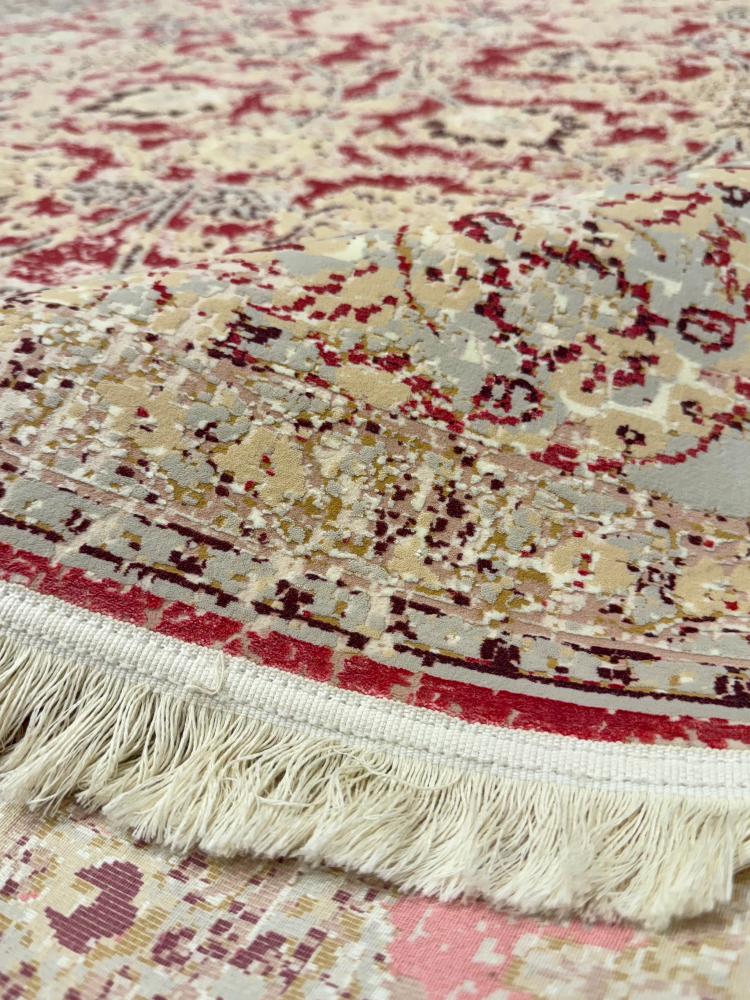 Close-up of a patterned rug with fringes on a wooden floor.